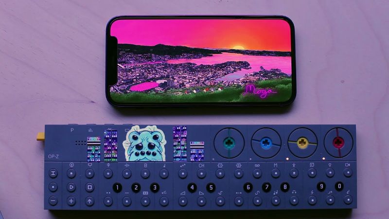 Phone screen showing a pink Bergen sunset above an OP-Z synth