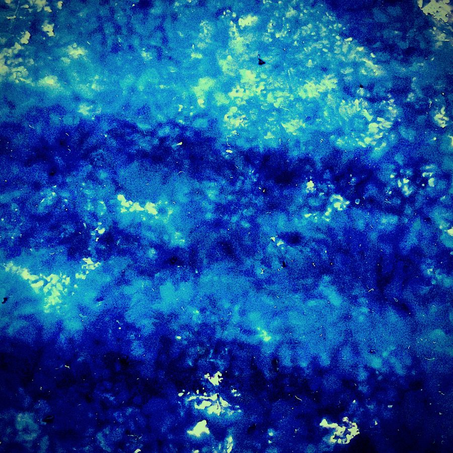 Abstract: deep blue mottled texture with pale green flecks
